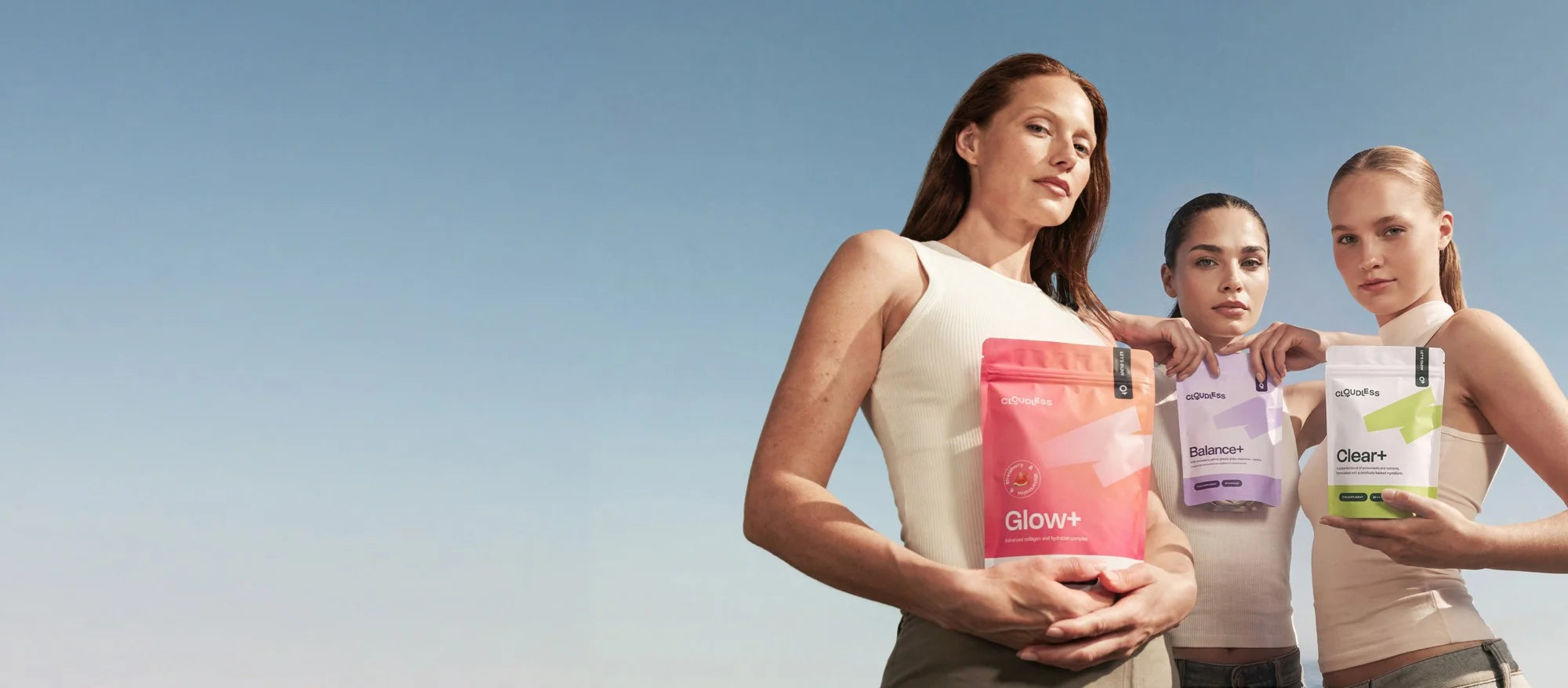 Drie vrouwen met Glow+, Balance+ en Clear+ tegen een blauwe lucht