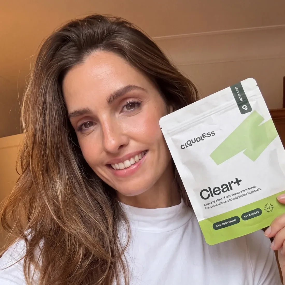 A smiling woman with clearer skin holds Clear+